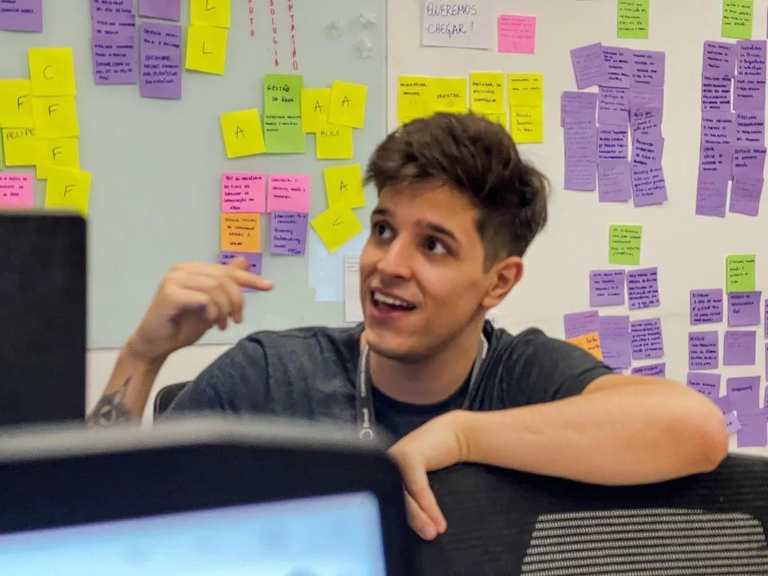 Vinicius during a workshop, talking in front of a wall of colored sticky notes